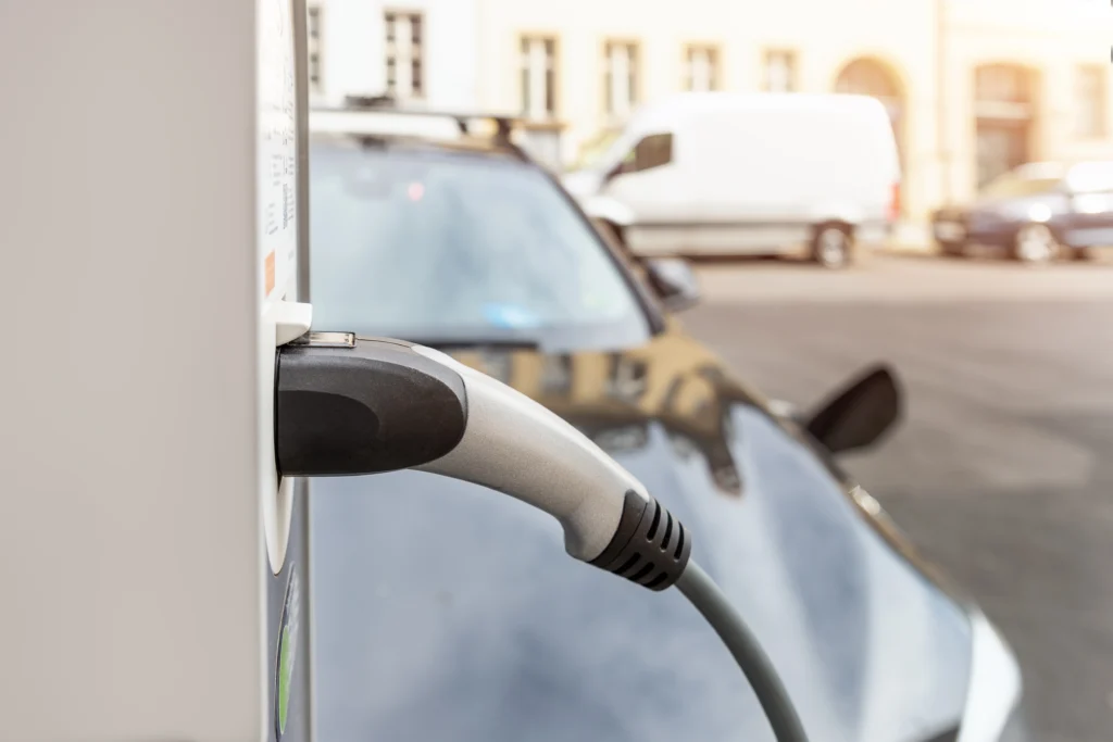Elektroauto lädt an öffentlicher Ladesäule in städtischer Umgebung, Typ-2-Stecker eingesteckt.